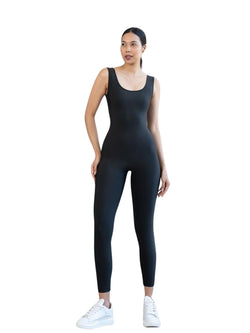 Person in einem Lismina 1400 Scrunch Butt Jumpsuit in Schwarz und weißen Turnschuhen, posiert vor einem schlichten Hintergrund.