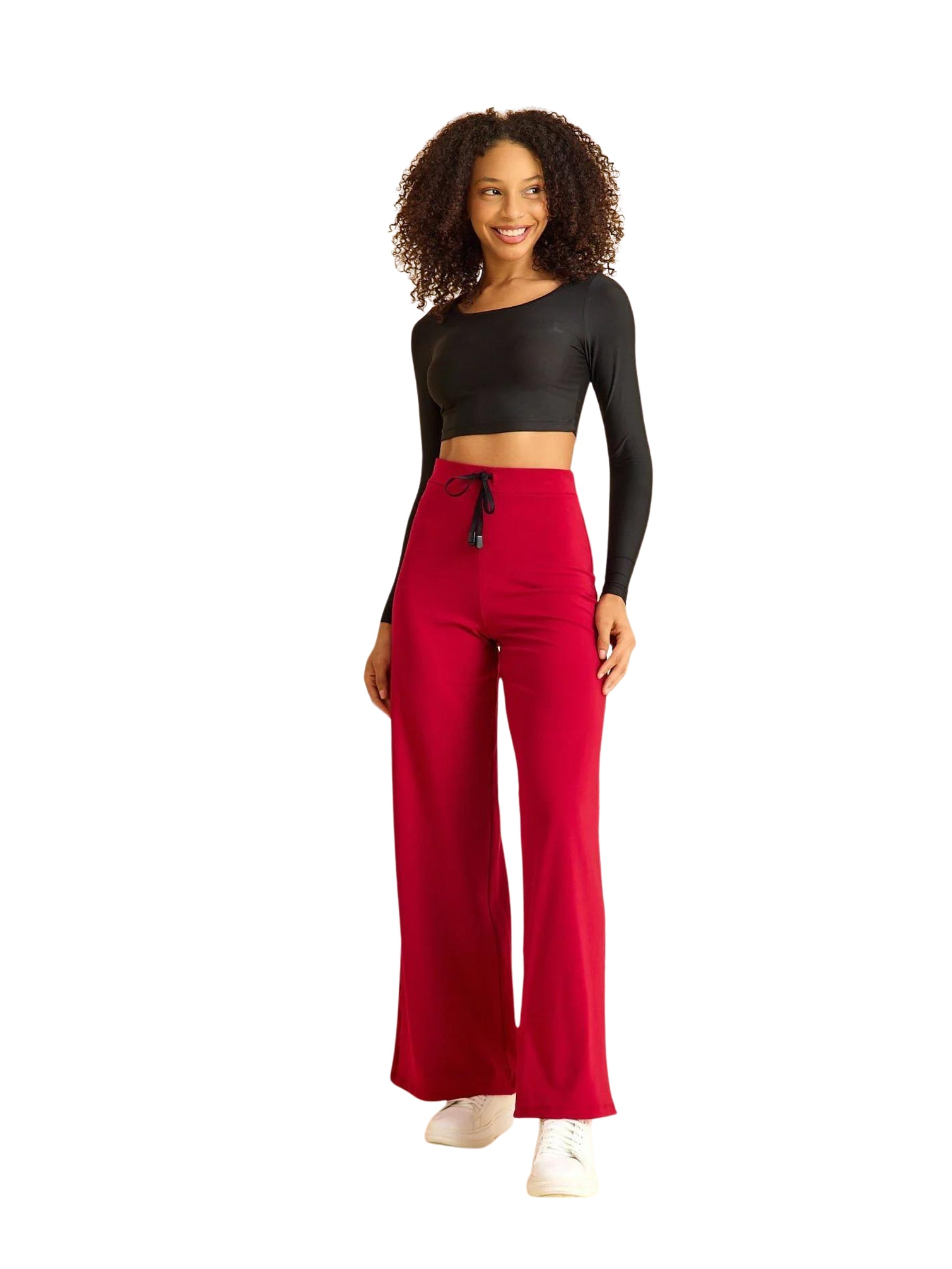 Frau in schwarzem Crop-Top und Lismina 448 Mumbai Yoga Hose in Bordeaux lächelt vor weißem Hintergrund.