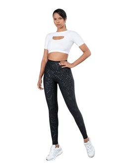 Eine Person in einem weißen bauchfreien Top und Leggings in Lederoptik von Lismina 467 Bilboa steht selbstbewusst vor einem weißen Hintergrund.