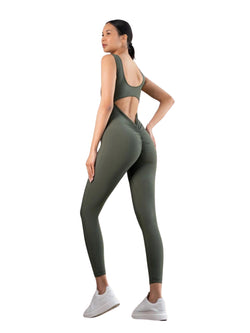 Eine Person steht selbstbewusst mit leicht abgewandtem Blick in einem Lismina 1402 Scrunch Butt Jumpsuit in Khaki und weißen Sneakers.