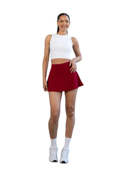 Frau, die den 484 Rock von Lismina in Bordeaux und ein weißes Crop-Top trägt und vor einem weißen Hintergrund steht.