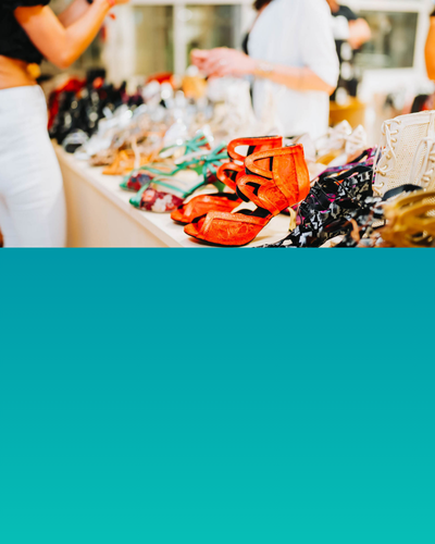 Frauen kaufen in einem Geschäft Schuhe ein. Auf einem Tisch sind verschiedene bunte Schuhe ausgestellt.