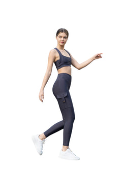 Frau posiert selbstbewusst in Lisminas anthrazitfarbenen 317 High Waist Leggings und Sneakers auf weißem Hintergrund.