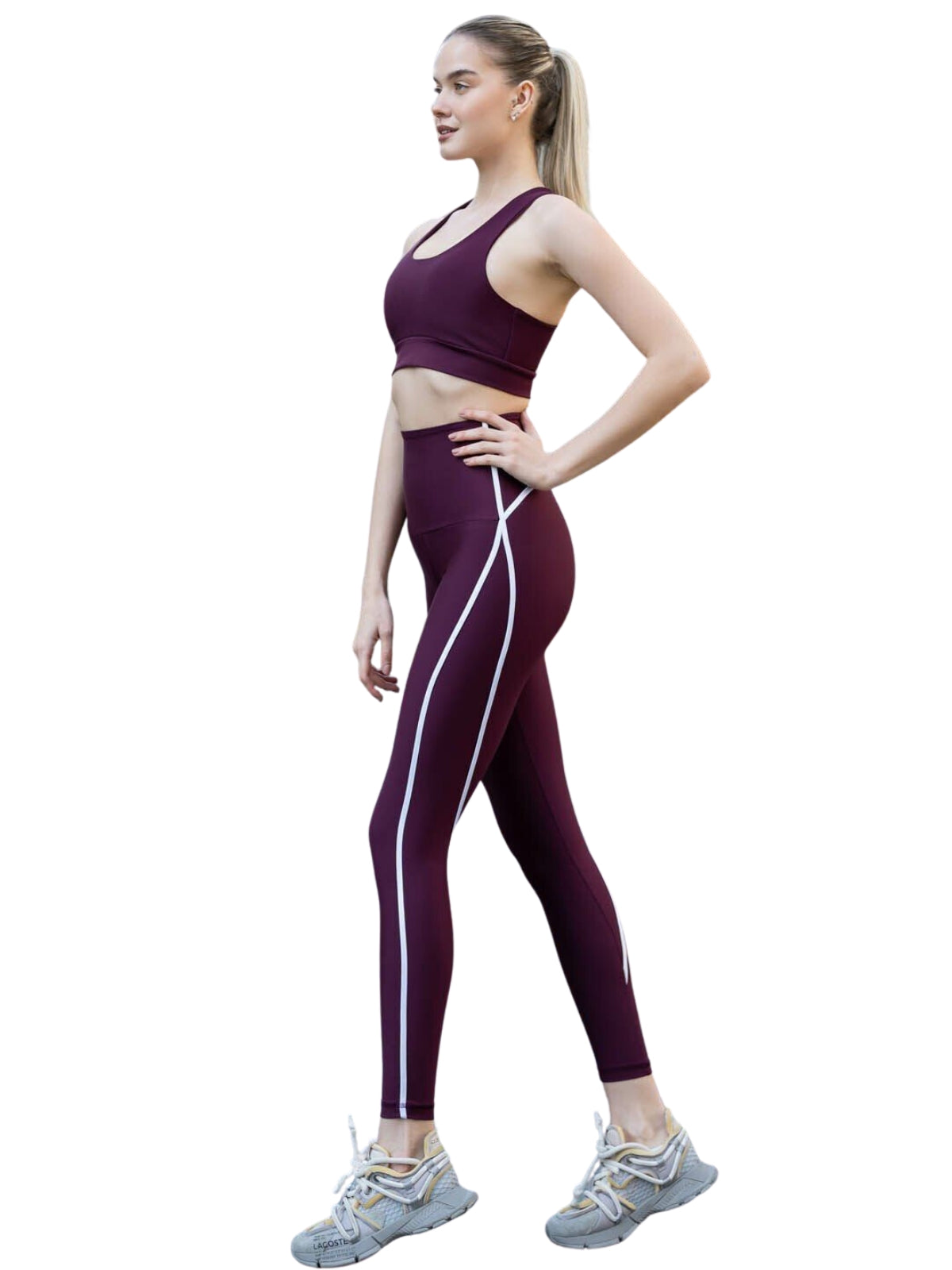 Frau in 373 Menton Leggings von Lismina, lächelnd, Seitenansicht, weißer Hintergrund; trägt burgunderfarbene Sportbekleidung, graue Turnschuhe.