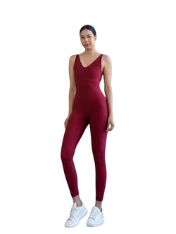 Eine Person in einem bordeauxroten Lismina 2101 Double Cross Jumpsuit und weißen Turnschuhen steht vor einem weißen Hintergrund.