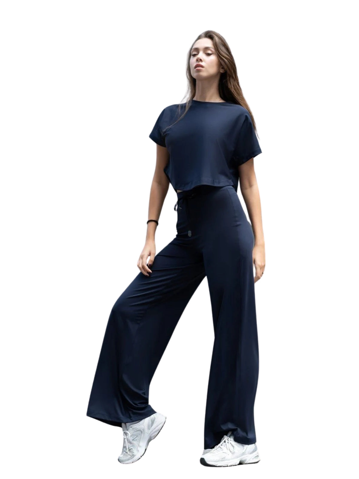 Person im Lismina 048 Yoga-T-Shirt in Marineblau und weiten Hosen, trägt weiße Turnschuhe auf weißem Hintergrund.