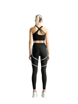 Blondes Mädchen mit Pferdeschwanz, das Lisminas 394 Orly Sport Leggings in Schwarz & Weiß trägt, steht mit dem Gesicht abgewandt vor einem weißen Hintergrund.