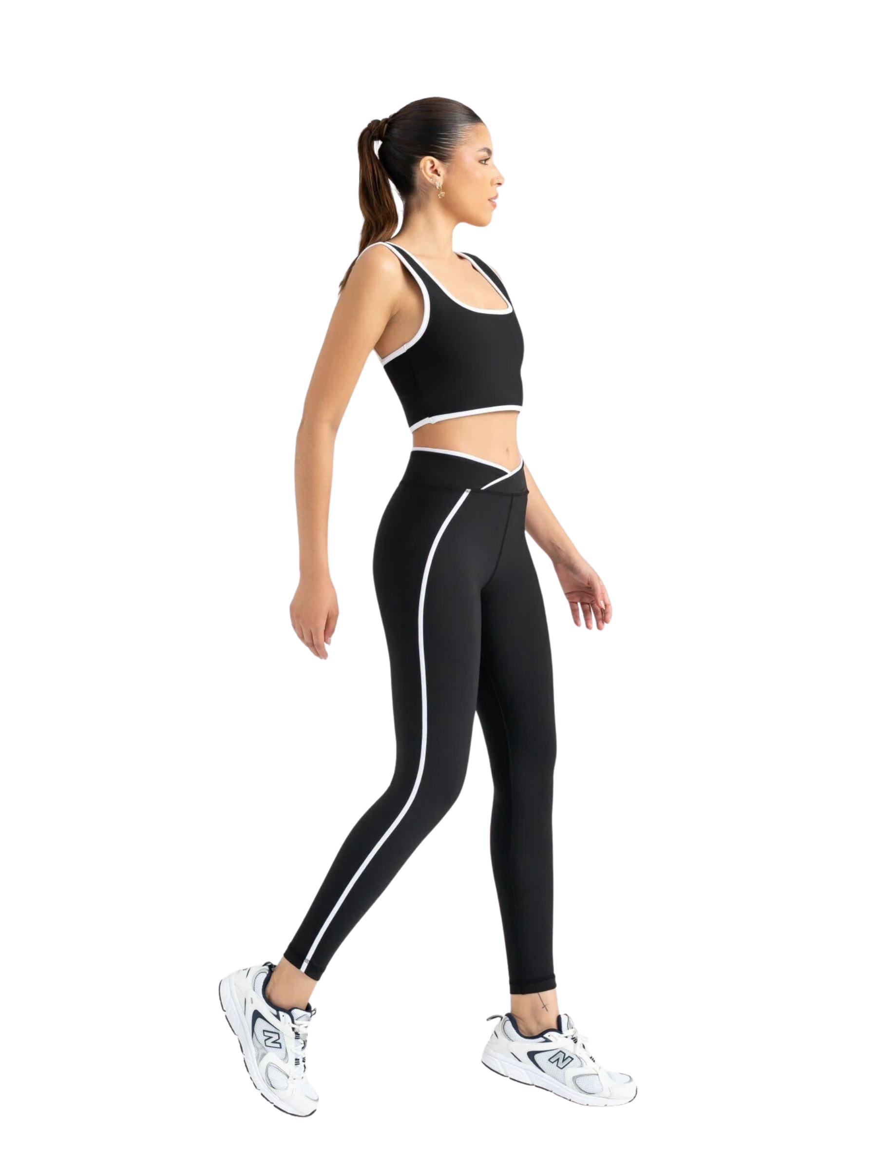 Frau in Lismina 556 V Line Sport Leggings in Schwarz, geht im Profil vor weißem Hintergrund.