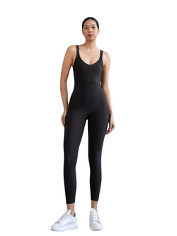 Einzelperson in einem Lismina 1600 Ganzkörper-Jumpsuit, Schwarz, rückenfrei, und weißen Turnschuhen auf weißem Hintergrund.