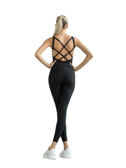 Person im Lismina 2100 Double Cross Jumpsuit, steht mit in die Hüften gestemmten Armen und trägt weiße Turnschuhe.