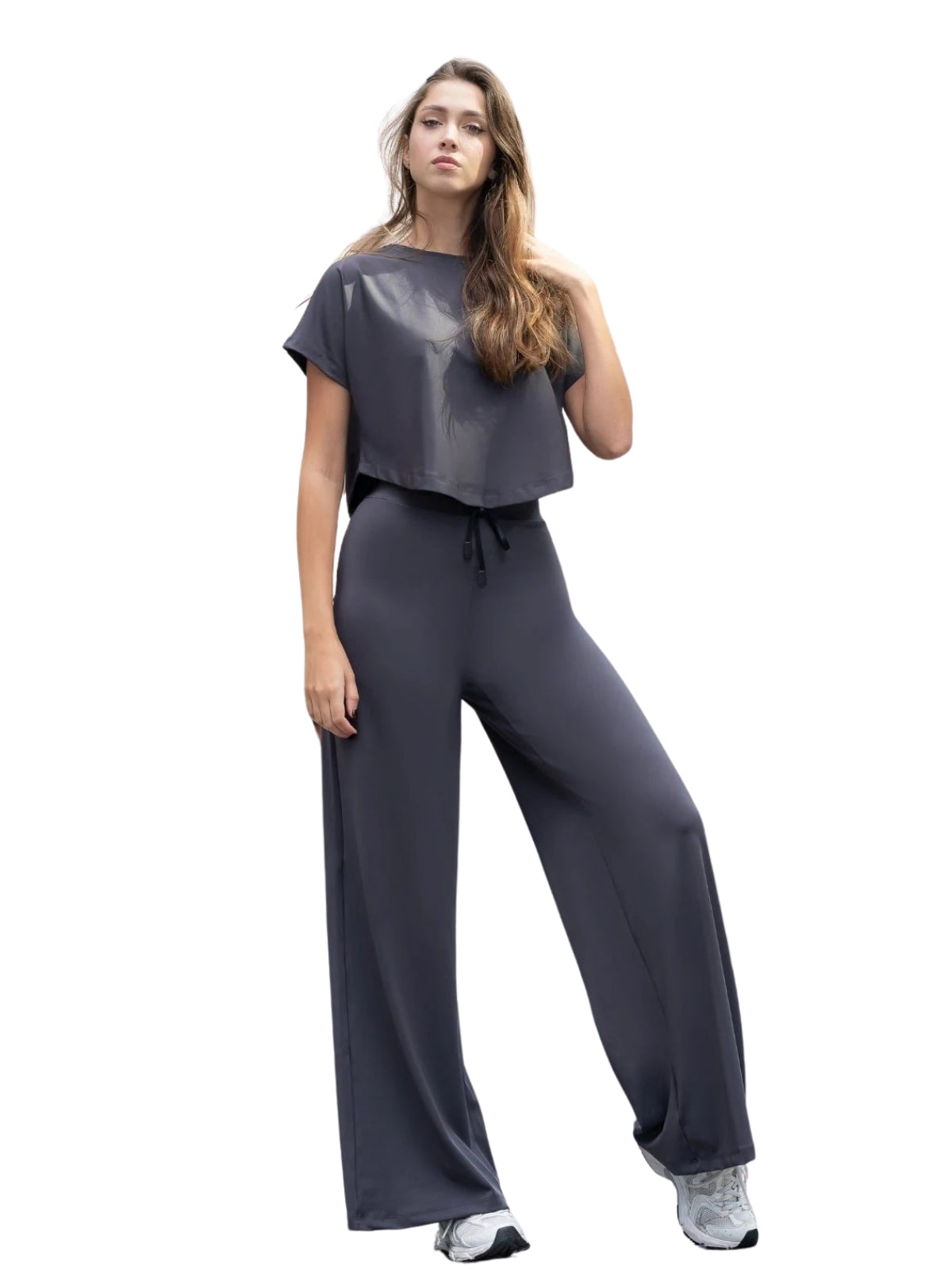 Person in einem Lismina 095 Yoga T-Shirt in Anthrazit, steht mit neutralem Gesichtsausdruck da, bereit für Yoga.