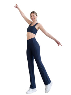 Person in Lisminas 435 Pocket Schlagleggings (Navyblau) und weißen Sneakers, Arme erhoben, lächelnd auf weißem Hintergrund.