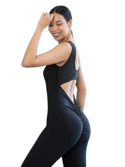 Frau im 1400 Scrunch Butt Jumpsuit von Lismina in Schwarz posiert mit der Hand auf dem Kopf und lächelt stilvoll.