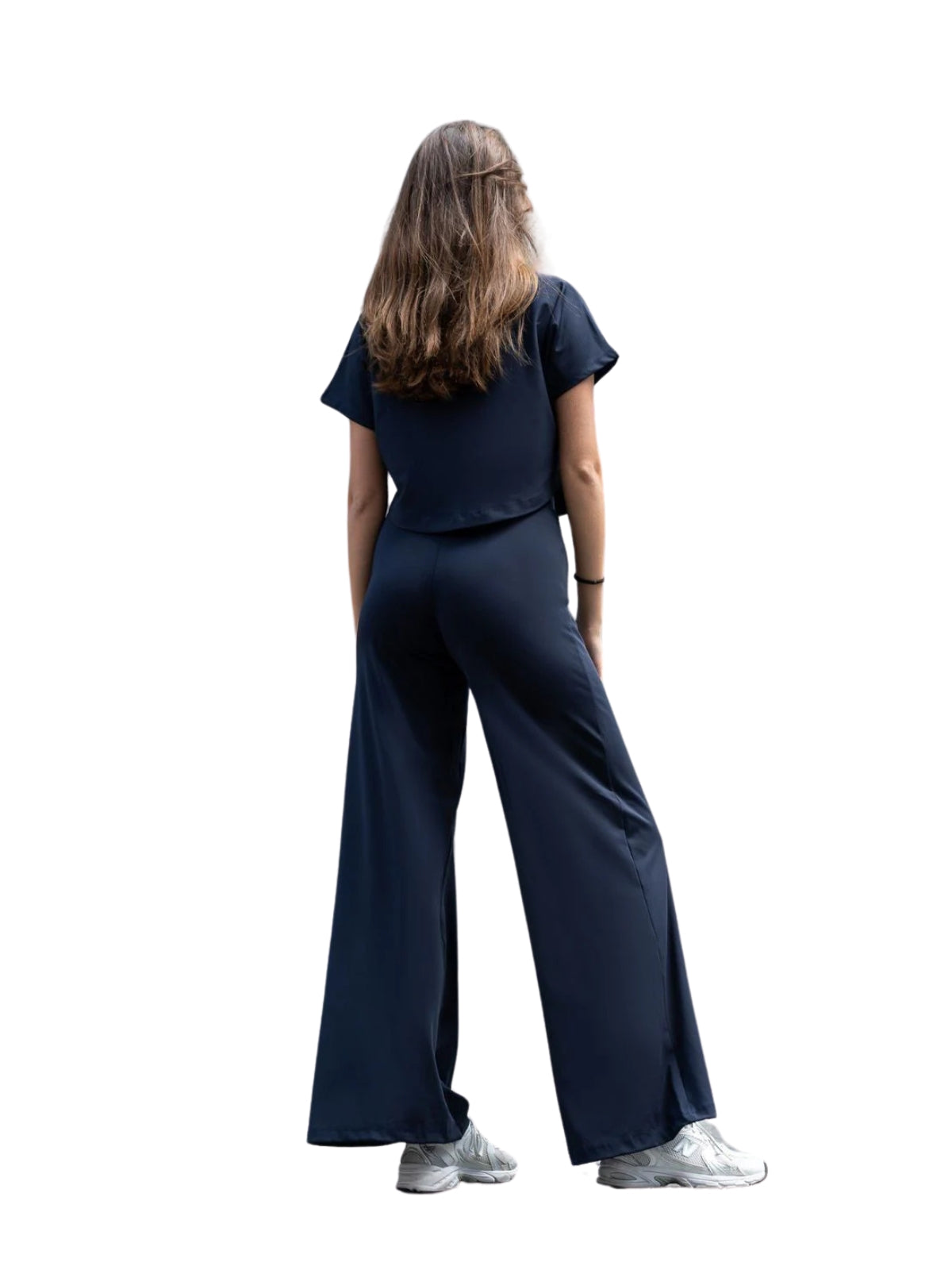 Frau mit langen Haaren in Lisminas 048 Yoga T-Shirt in Marineblau und Turnschuhen, die Bewegungsfreiheit zur Schau stellt.