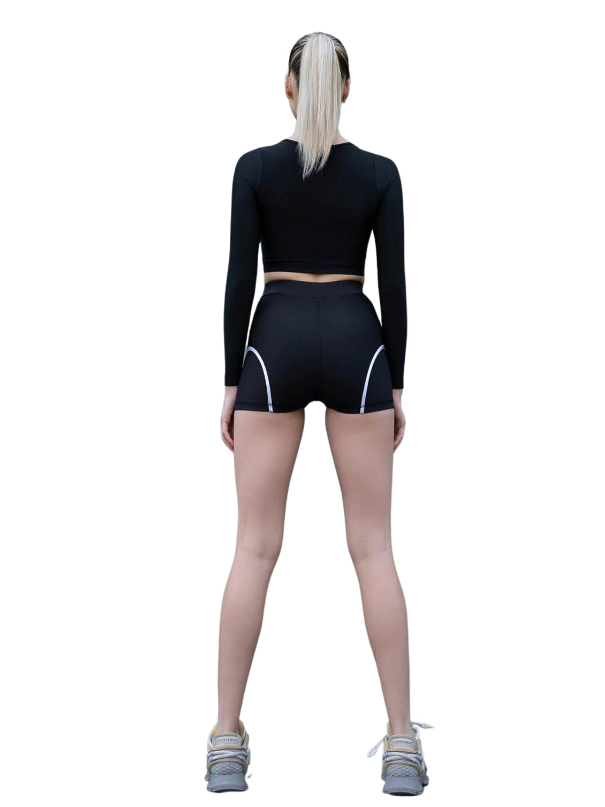 Person in 5036 Ales Mini Shorts in Schwarz von Lismina und Sneakers steht mit dem Rücken zur Kamera.