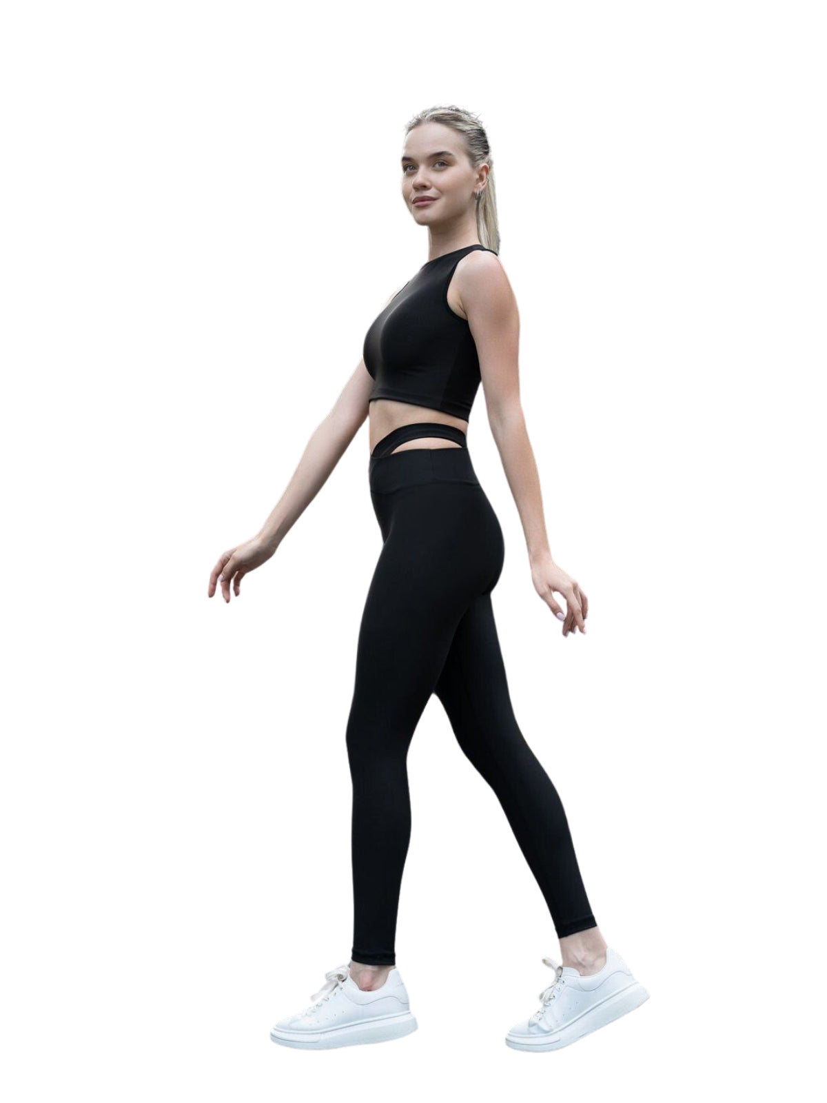 Eine Person in Lisminas schwarzen 814 Extra High Waist Leggings und weißen Sneakers läuft vor einem schlichten weißen Hintergrund.