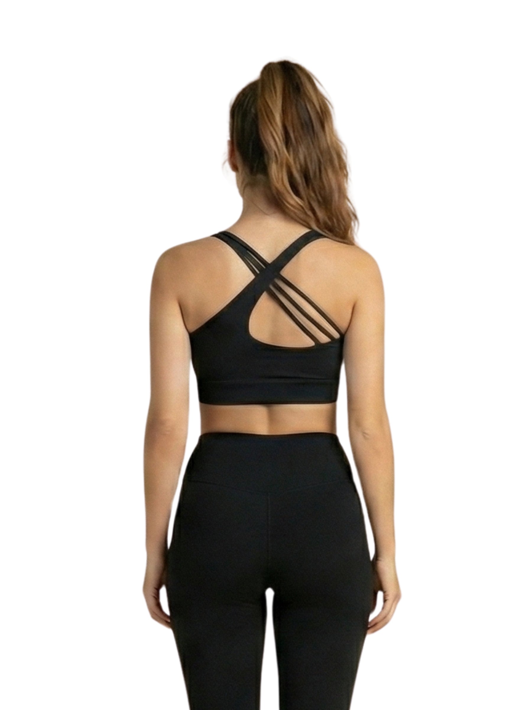 Frau im Lismina 396 Bron Sport Bra in Schwarz mit überkreuzten Trägern steht, Blick von der Kamera weg.