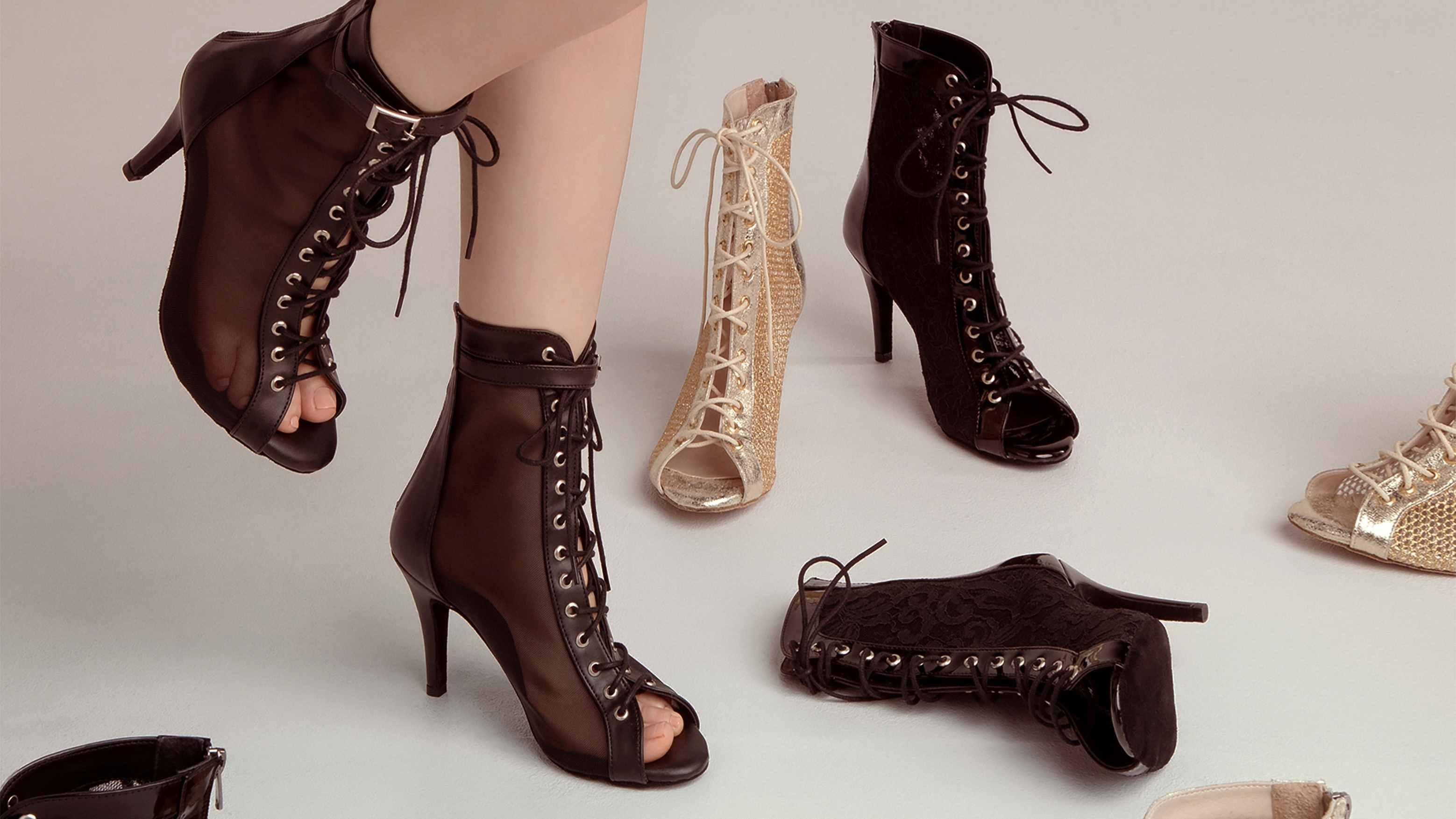 Eine Auswahl offener Schnürstiefeletten mit hohen Absätzen in Schwarz und Beige auf hellem Untergrund.