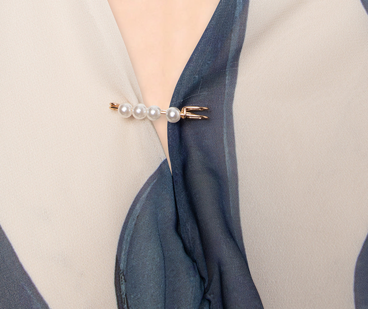 Nahaufnahme eines Blusenausschnitts mit Dancing Queens Sicherheitsnadeln mit Perlen im Set, mit drei Perlen.