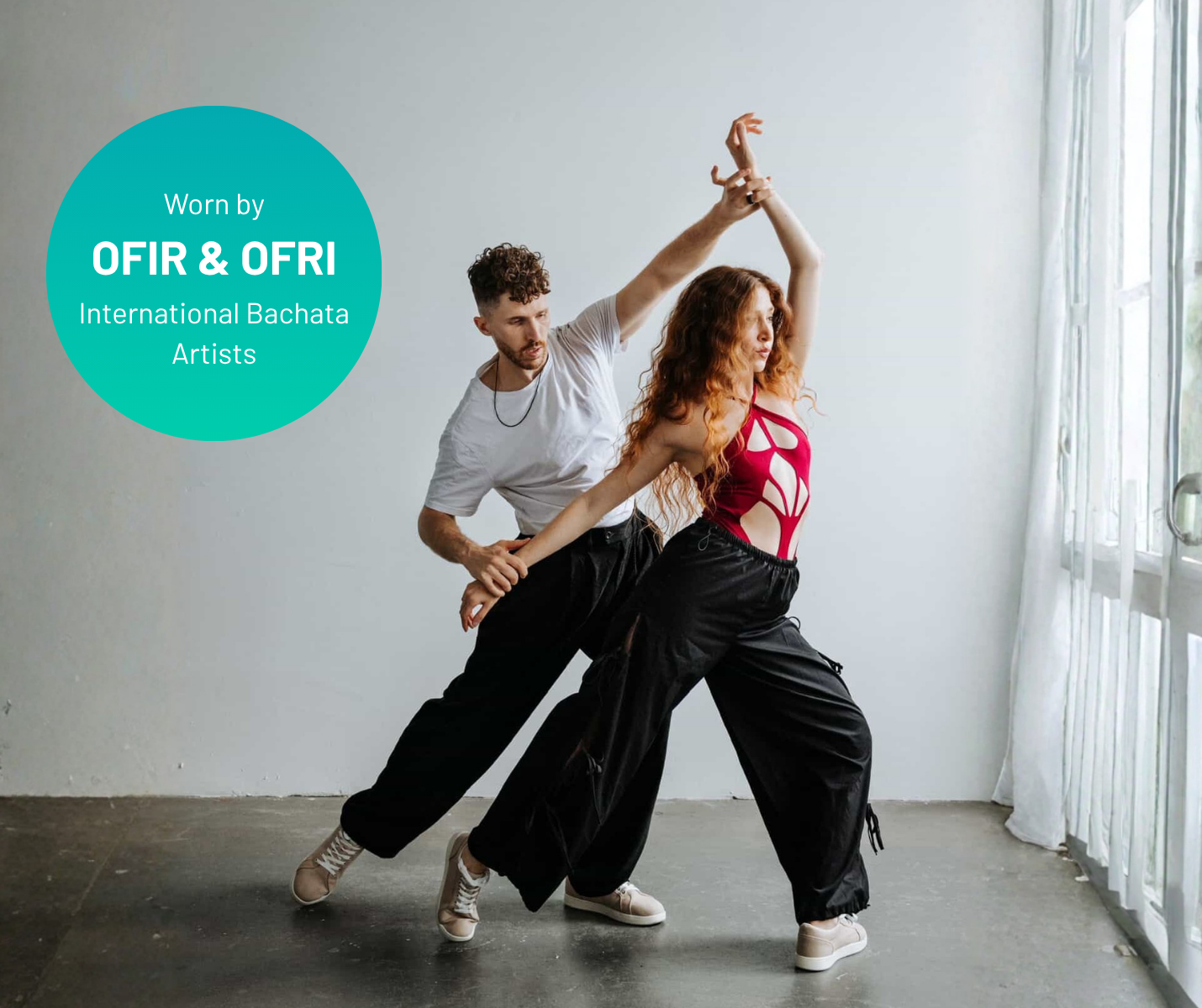 Zwei Tänzerinnen in weiten schwarzen Hosen präsentieren den „Dancing Queens SMOVE Dance Sneaker“ in der Farbe „Weiss“.