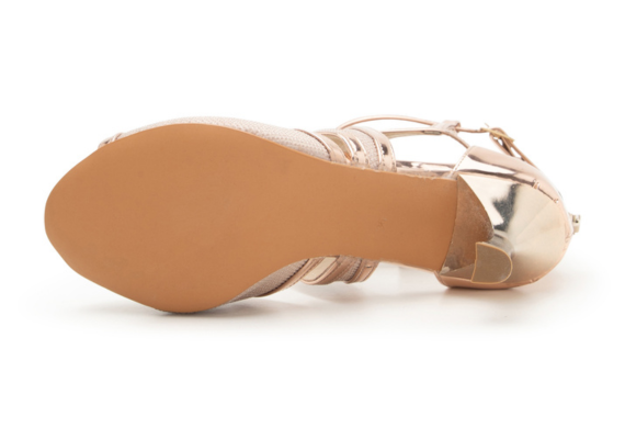 Unteransicht eines hochhackigen Damenschuhs mit beiger Sohle und goldfarbenen Metallic-Riemen am Schaft.