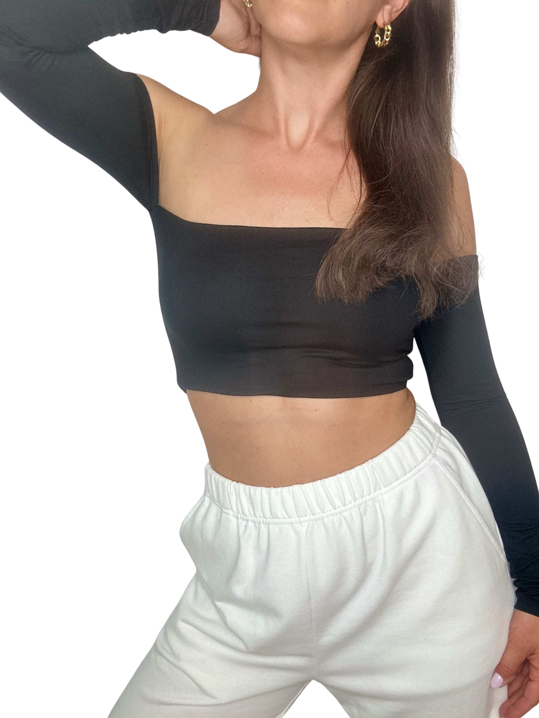Frau in MODANCE Dancewear Top Eli Long in Solid Black und weißer Jogginghose, posiert mit erhobenem Arm.