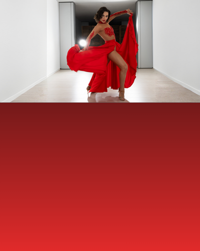 Eine Frau in einem fließenden roten Kleid tanzt in einem modernen, weißen Flur mit hellen Lichtern hinter ihr.