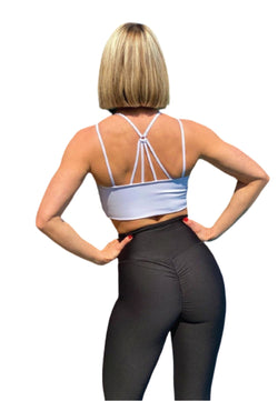 Person mit Bob-Haarschnitt, die ein weißes Oberteil und Lisminas 737 Scrunch Butt Leggings in Schwarz trägt, die Hände in die Hüften gestemmt.