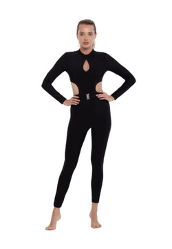 Person in einem Esmeralda Clara-Jumpsuit in Schwarz mit dekorativer Schnalle, bereit zum Tanzen vor einem weißen Hintergrund.