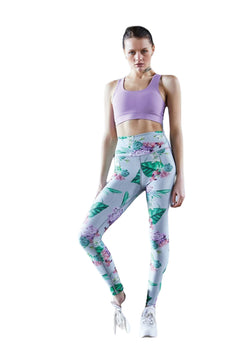 Person trägt ein lila Sportoberteil, Lismina 1081 Extra High Waist Leggings in Grün und weiße Turnschuhe mit den Händen auf den Hüften.