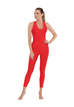 Person im Lily-Jumpsuit von Esmeralda in einer Yoga-Pose mit einer Hand auf der Hüfte vor einem weißen Hintergrund.