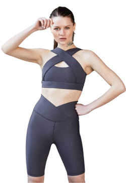 Frau posiert in einem Lismina Antrazit Crisscross-Sport-BH und 6017 Biker-Leggings vor einem weißen Hintergrund.