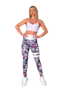 Frau in Lisminas weißem Sport-BH und geblumten Leggings 890 Extra High Waist Schwarz & Weiss, posiert selbstbewusst.
