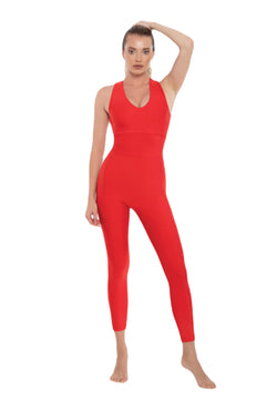 Eine Person trägt den Lily-Jumpsuit in Rot von Esmeralda und posiert barfuß anmutig, als wäre sie mitten beim Yoga, vor einem weißen Hintergrund.