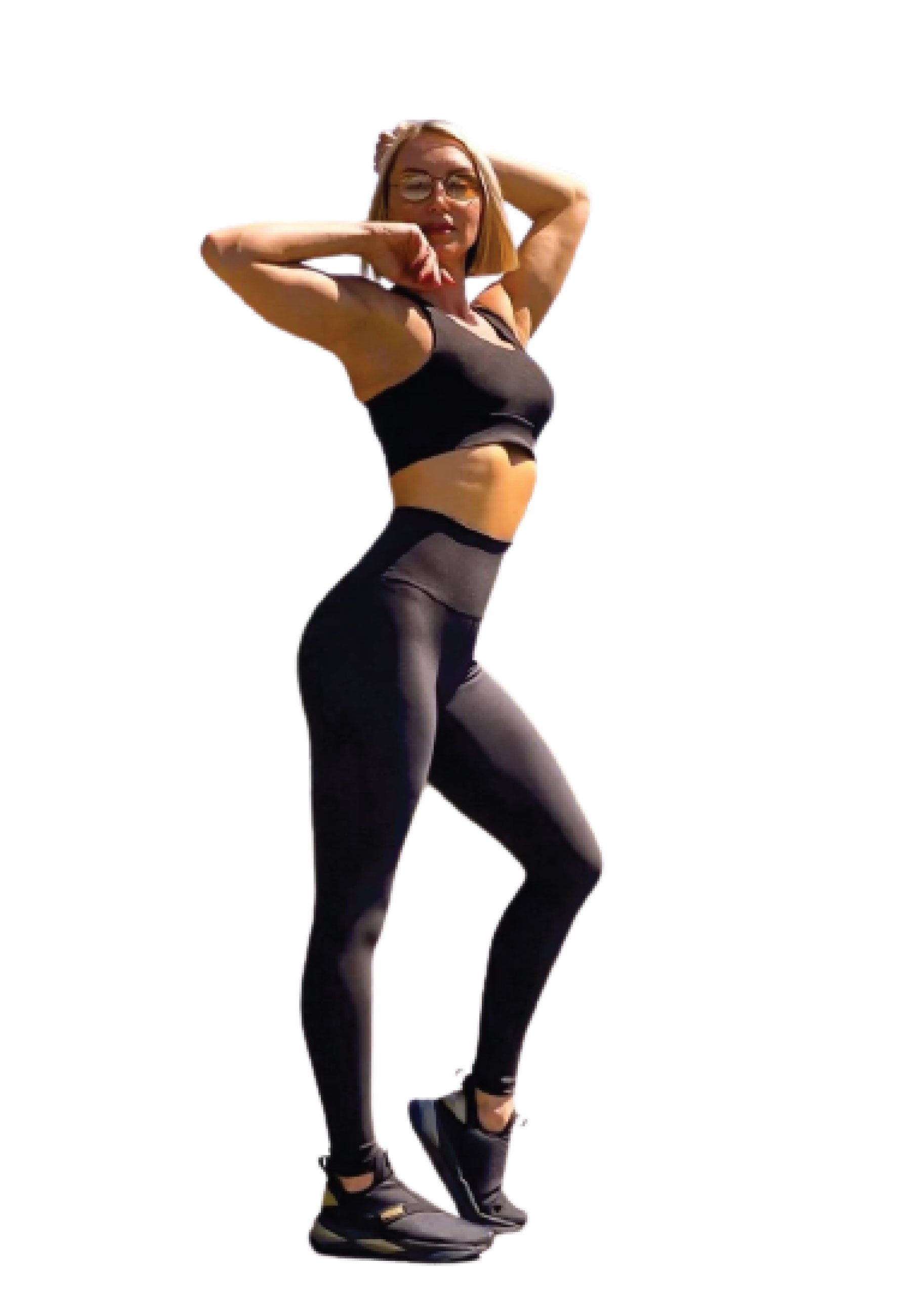 Person in Lisminas 101 Single Crossed Sport Bra in Schwarz, die selbstbewusst in eleganter schwarzer Sportbekleidung und Turnschuhen posiert.
