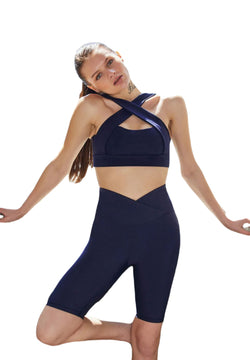 Eine Person in Lisminas 6014 Biker-Leggings Ve Waist in Marineblau posiert mit einem angewinkelten Knie vor einem schlichten Hintergrund.