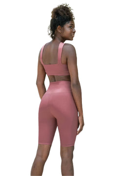 Eine Frau in Lisminas 6027 Dark Rose Biker Leggings posiert über ihrer Schulter und präsentiert einen Sport-BH und Leggings.