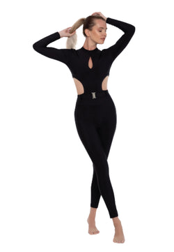 Barfüßige Frau in Esmeraldas Clara-Jumpsuit in Schwarz mit Ausschnitten posiert anmutig vor einem weißen Hintergrund.