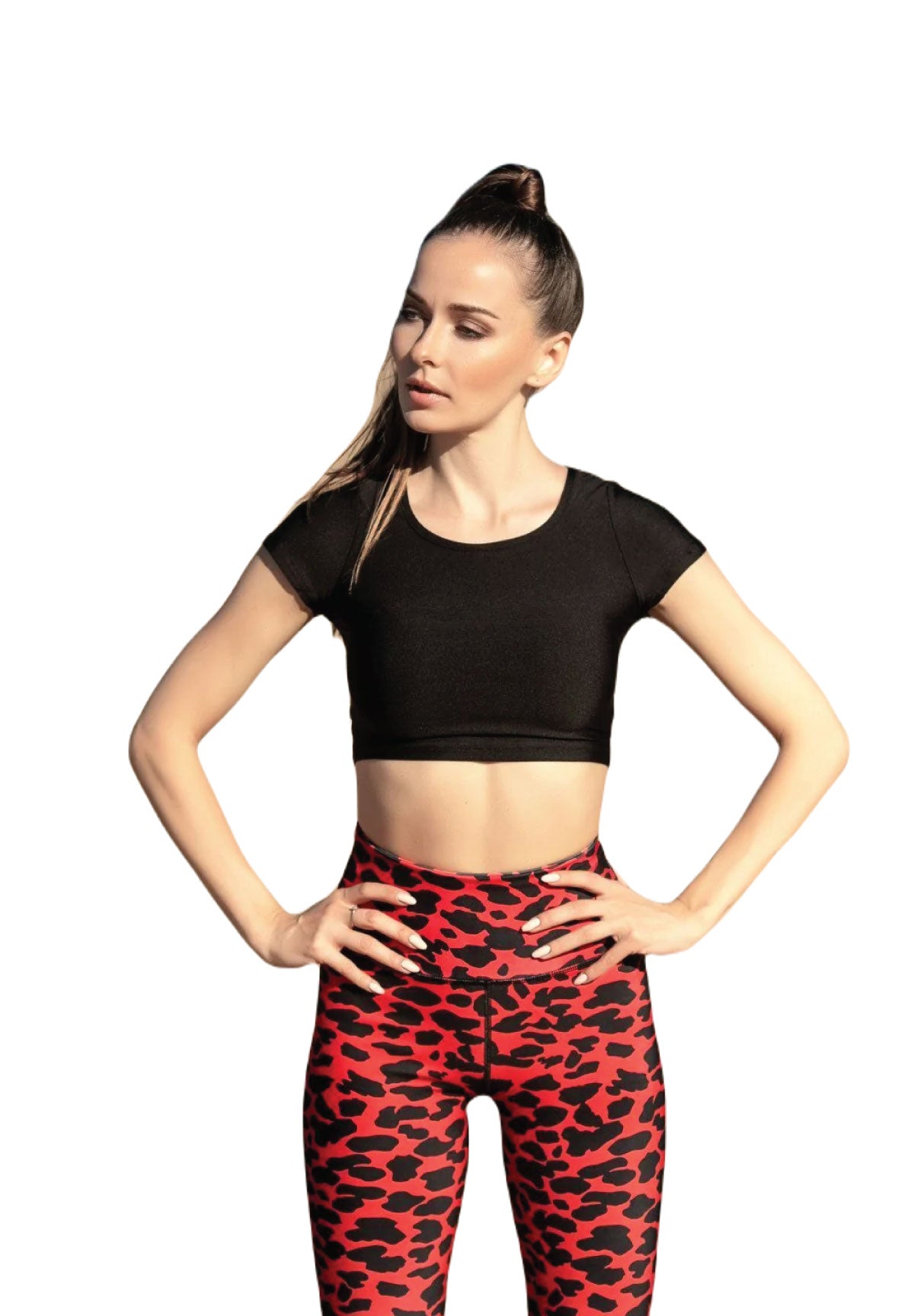 Frau in einem T-Shirt von Lismina 995 Schwarz und Leggings mit rotem Leopardenmuster, steht mit den Händen auf den Hüften und schaut zur Seite.