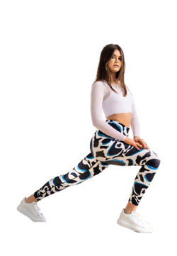 Frau trägt Lismina 1188 High Waist Leggings in Blau, Weiß und Schwarz und streckt sich in Sportschuhen auf einem Knie.