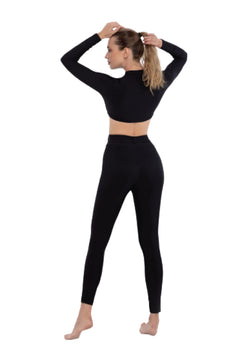 Frau in einem Clara-Jumpsuit von Esmeralda, barfuß, richtet ihr Haar.