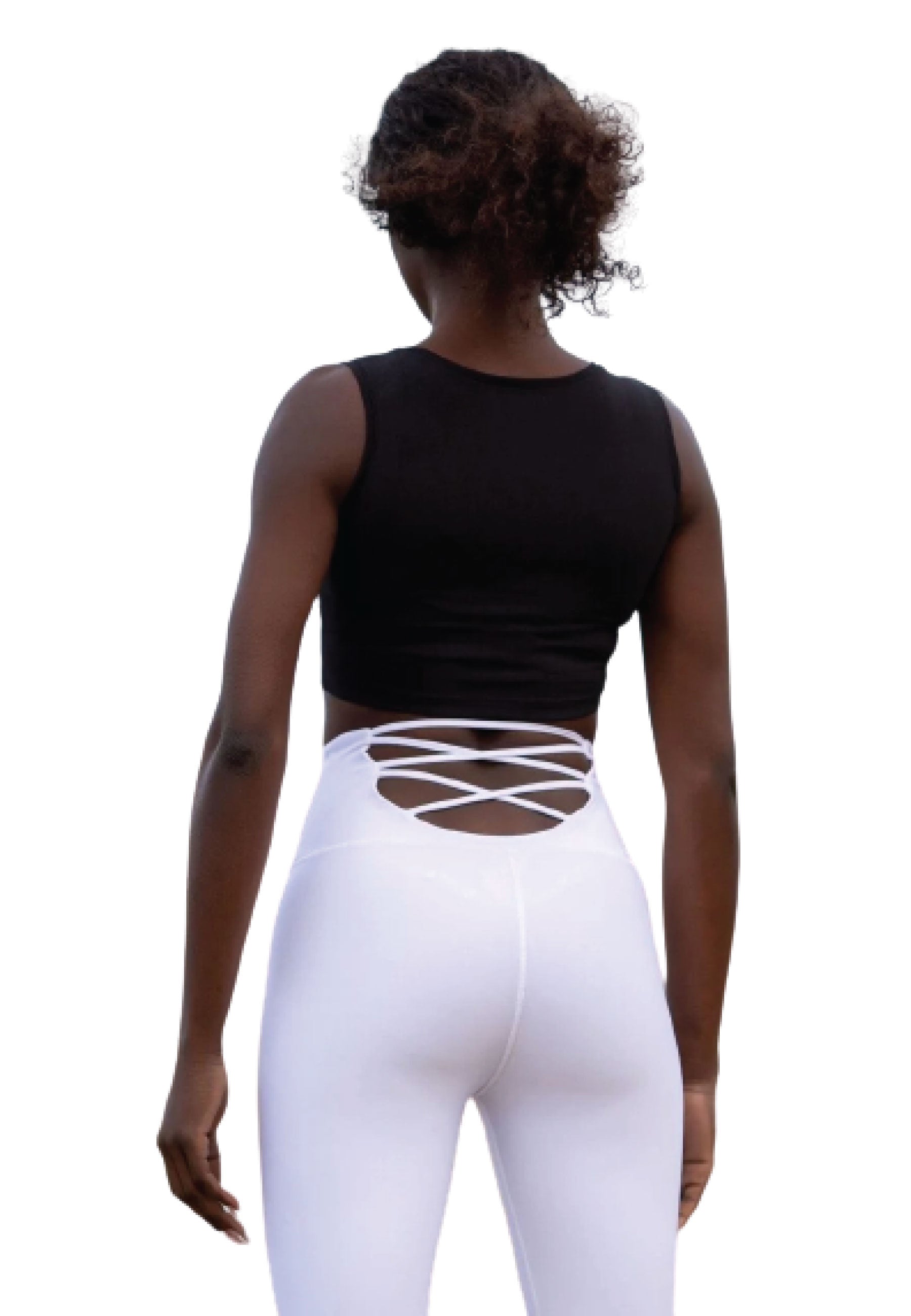 Person mit Locken in einem schwarzen Sport-BH mit Reißverschluss von Lismina und weißen Crisscross-Leggings, steht vor Weiß.