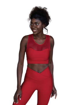 Das Model Lismina lächelt in einem 204 Sport-BH mit Tülldetails in Rot vor weißem Hintergrund.