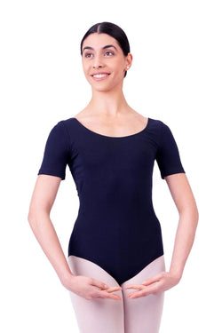 Lächelnde Person in einem marineblauen Rumpf R3100 Kurzarm-Body, die in der ersten Ballettposition auf Weiß mit rosa Strumpfhosen posiert.