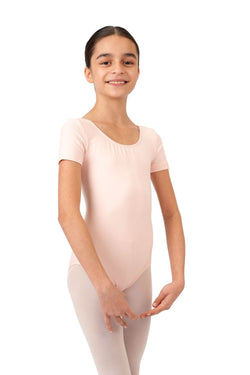 Ein junges Mädchen in Rumpfs R3100 Kurzarm-Body in Pink, lächelnd in Ballettpose, ein angenehmes Tragegefühl ausstrahlend.