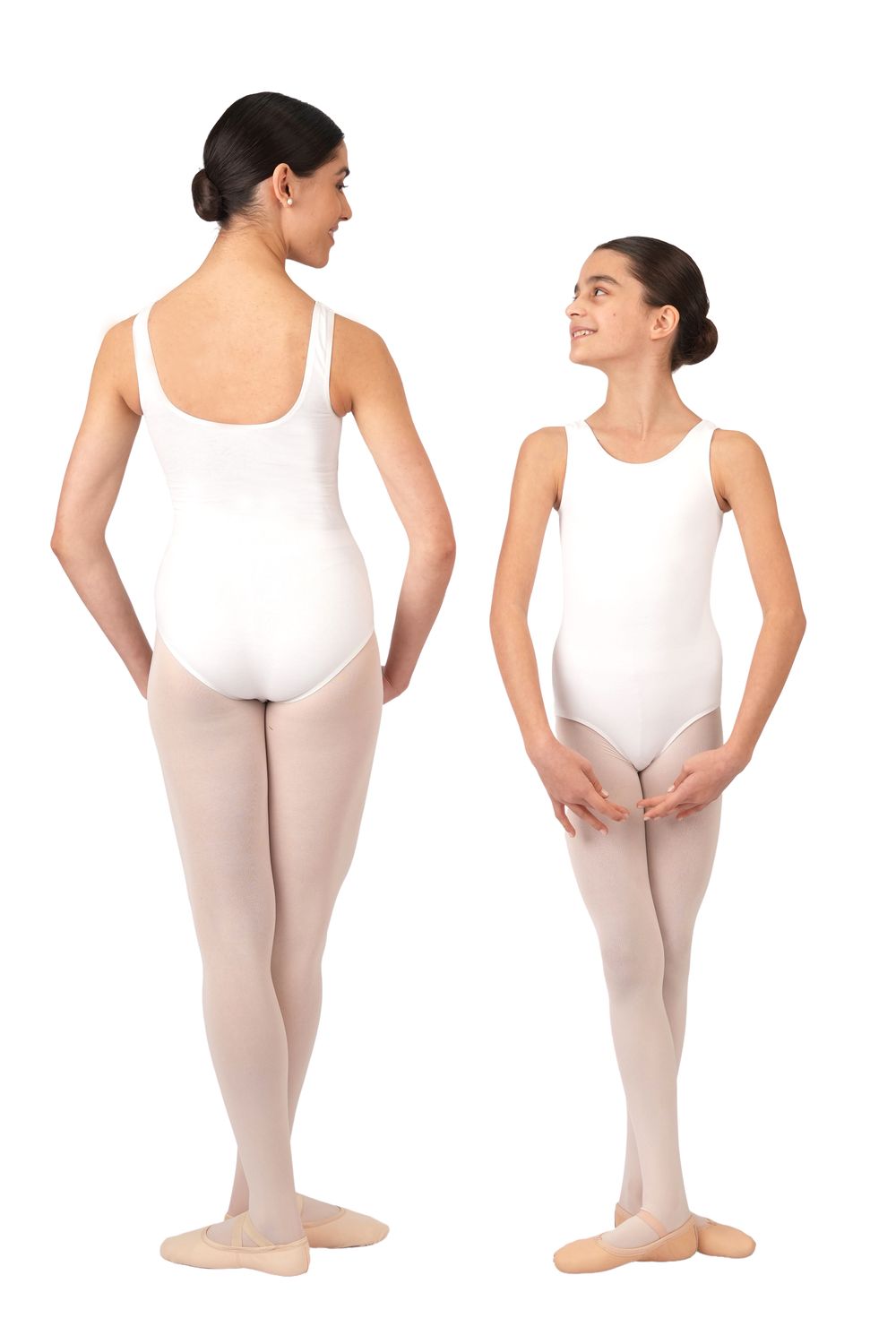 Zwei Balletttänzerinnen in Rumpfs R3101 weiße ärmellose Bodys lächeln sich gegenseitig im ersten Plié an.