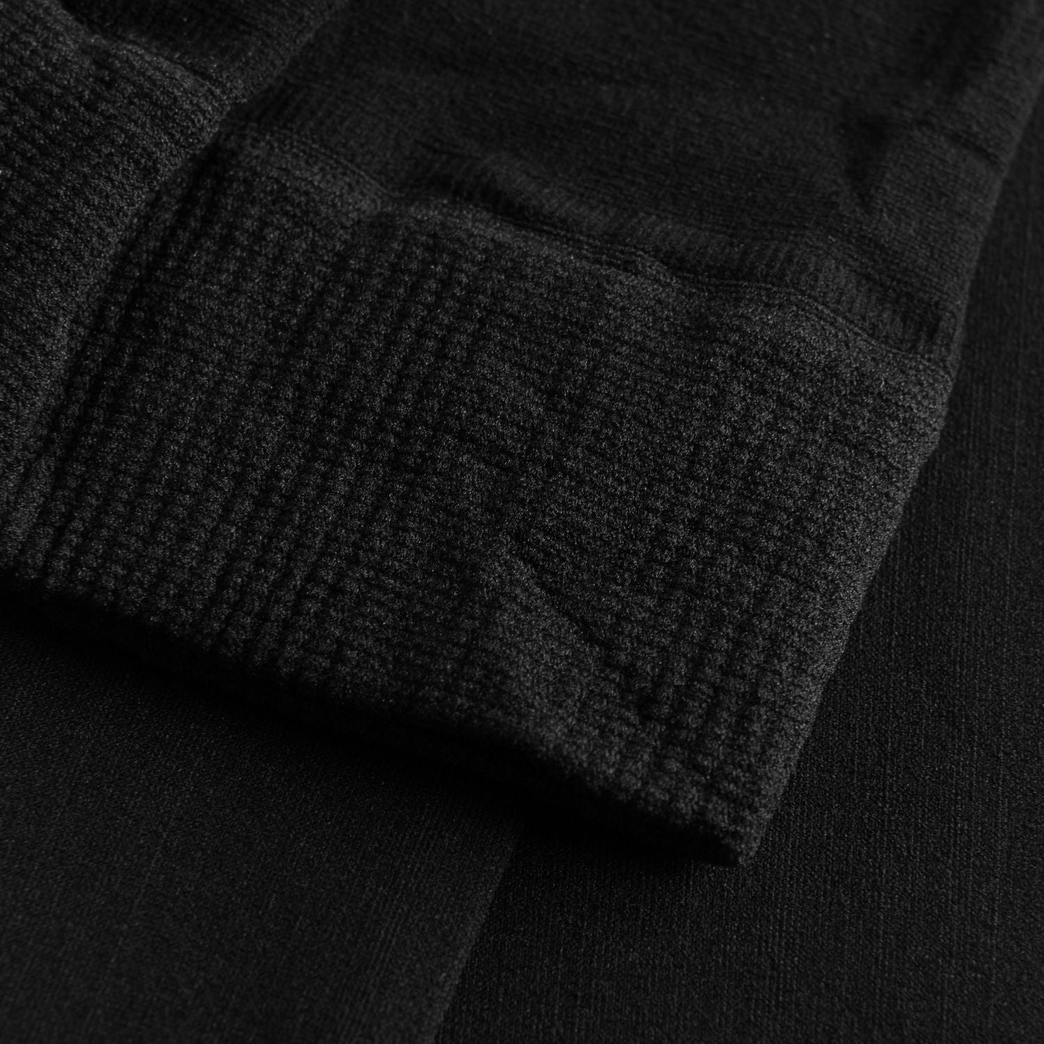 Nahaufnahme einer schwarzen, gerippten Stoffstruktur mit gefalteter Kante, die der 108 Economy Ballettstrumpfhose in Schwarz von Rumpf ähnelt.