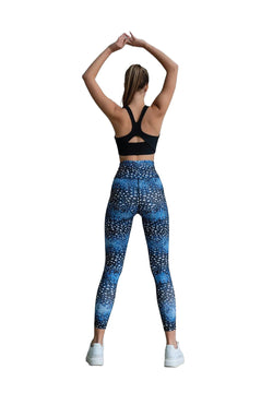 Person in schwarzem Sport-BH und Lisminas 325 Extra High Waist Leggings in Blau streckt sich mit erhobenen Armen.