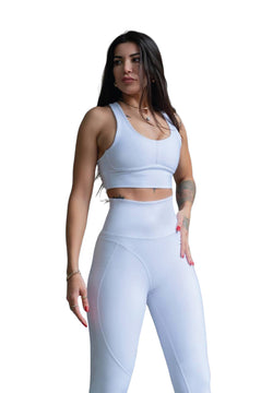 Eine Person in Lisminas 314 Winter High Waist Leggings in Weiss und hellblauer Sportbekleidung posiert selbstbewusst vor einem schlichten Hintergrund.