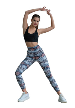 Person posiert in Lisminas 328 Extra High Waist Leggings in Braun & Blau, trägt Turnschuhe und hat die Arme anmutig erhoben.